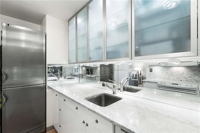 kitchen featuring sink, light stone counters, stainless steel fridge, white cabinets, and white range with electric stovetop