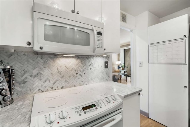 kitchen with light stone countertops, white cabinets, white appliances, and decorative backsplash