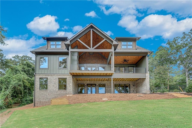 rear view of house featuring a yard, a balcony, and ceiling fan