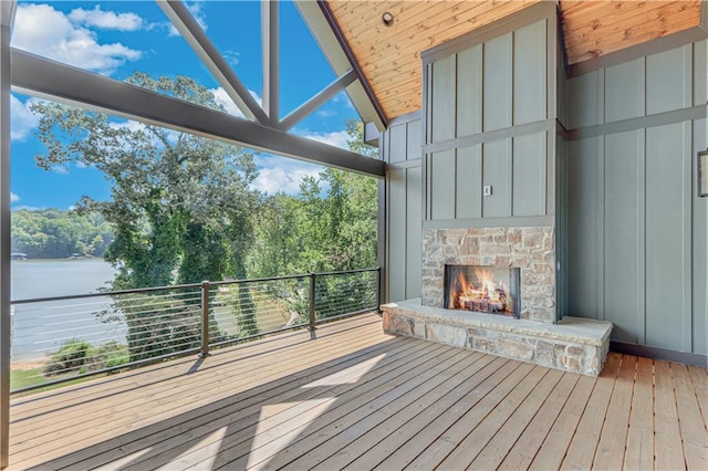 wooden terrace featuring a water view and a fireplace