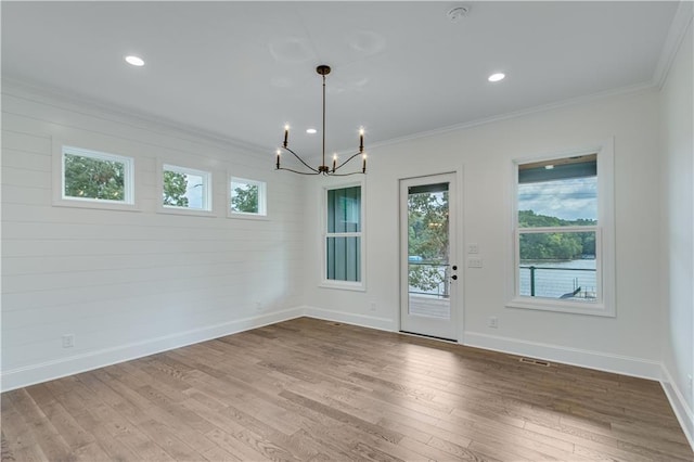 unfurnished dining area with crown molding, a chandelier, and hardwood / wood-style flooring