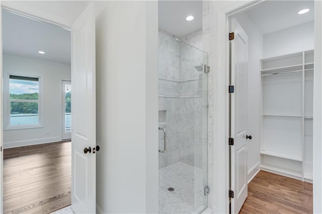 bathroom featuring hardwood / wood-style floors, a shower with shower door, and ornamental molding