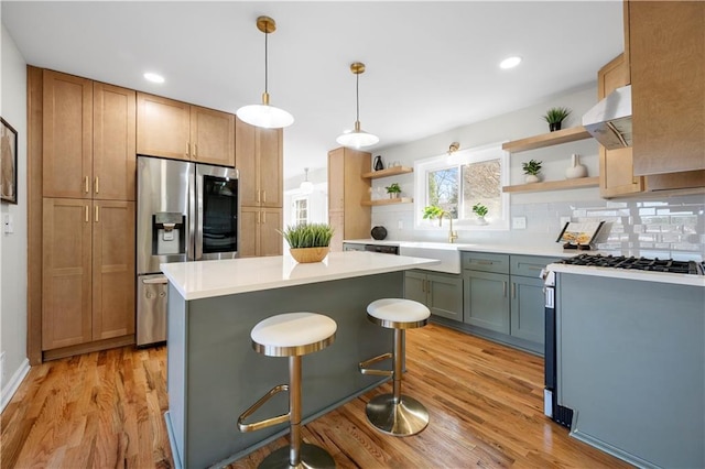 kitchen with a kitchen island, decorative light fixtures, sink, exhaust hood, and stainless steel appliances