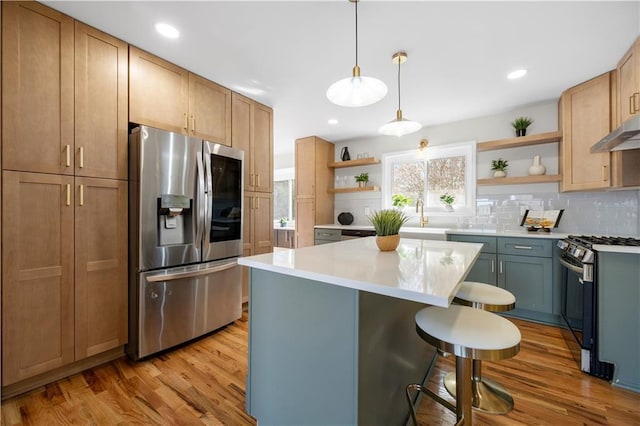 kitchen featuring pendant lighting, light hardwood / wood-style floors, a center island, and appliances with stainless steel finishes