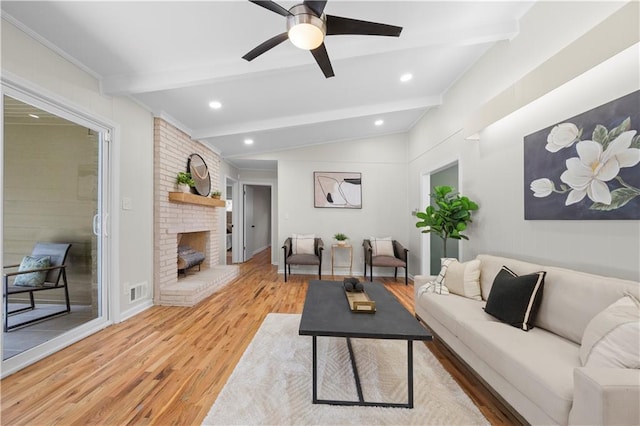 living room featuring a brick fireplace, hardwood / wood-style flooring, lofted ceiling with beams, and ceiling fan