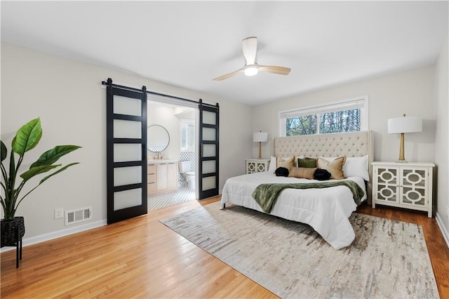 bedroom with ceiling fan, a barn door, and hardwood / wood-style floors