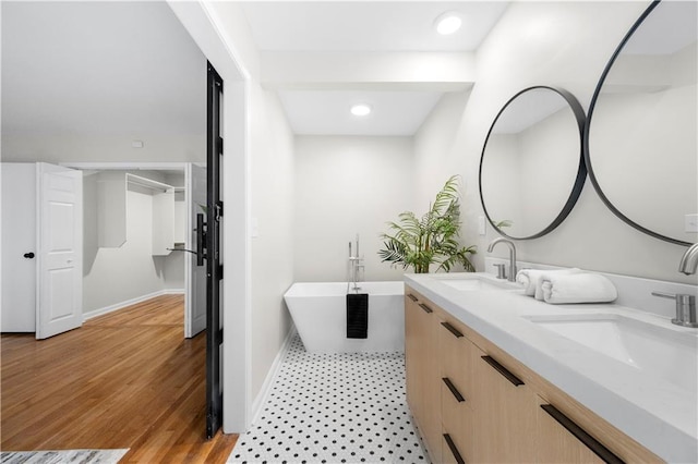 bathroom featuring vanity, wood-type flooring, and a bath