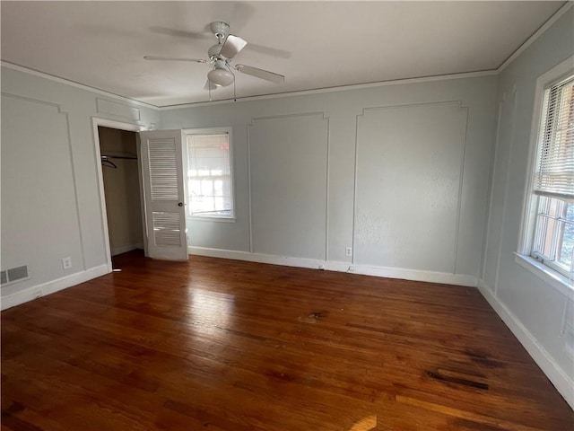 unfurnished bedroom featuring visible vents, multiple windows, wood finished floors, and crown molding