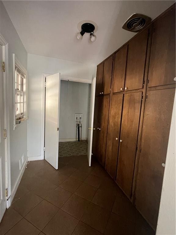 corridor with dark tile patterned floors and baseboards