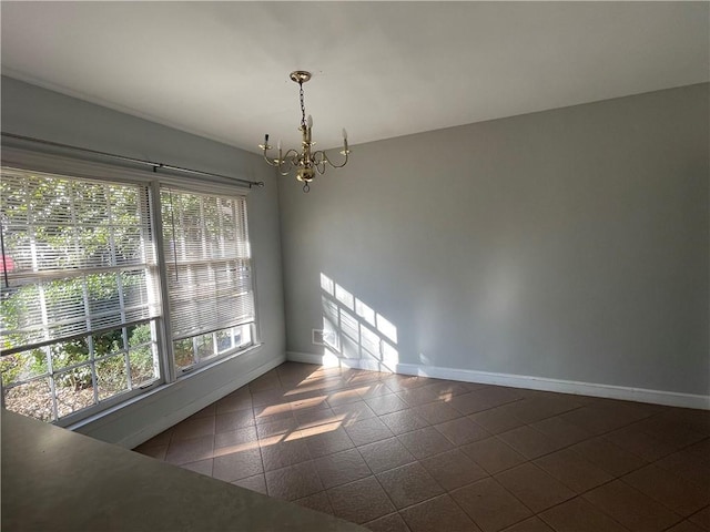 spare room featuring baseboards and a notable chandelier