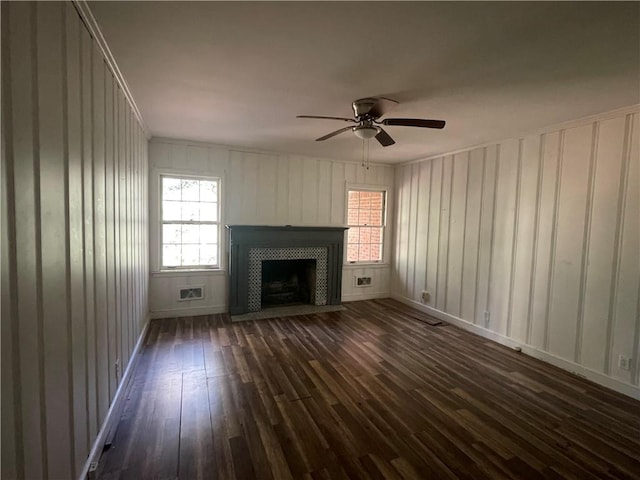 unfurnished living room with dark wood finished floors, a tiled fireplace, plenty of natural light, and a ceiling fan