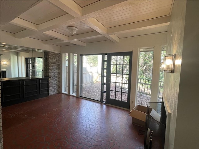 interior space featuring access to exterior, multiple windows, coffered ceiling, and beam ceiling