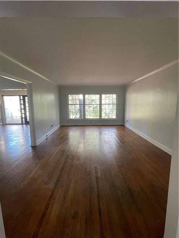 spare room featuring baseboards, ornamental molding, and dark wood-style flooring