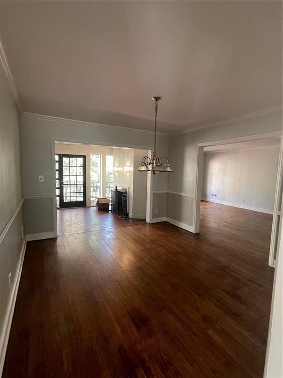 unfurnished dining area featuring dark wood finished floors, a notable chandelier, baseboards, and ornamental molding