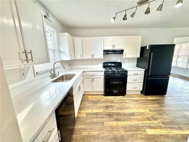 kitchen with white cabinetry, sink, light stone counters, and black appliances