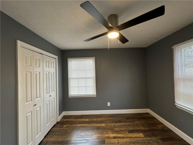 unfurnished bedroom featuring ceiling fan, dark hardwood / wood-style floors, a textured ceiling, and a closet