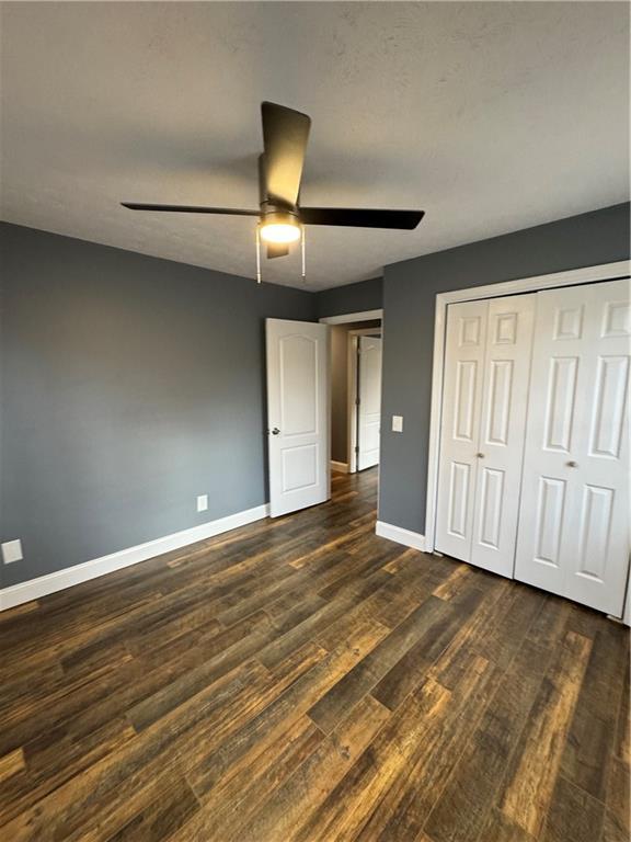 unfurnished bedroom featuring ceiling fan, dark hardwood / wood-style floors, and a closet