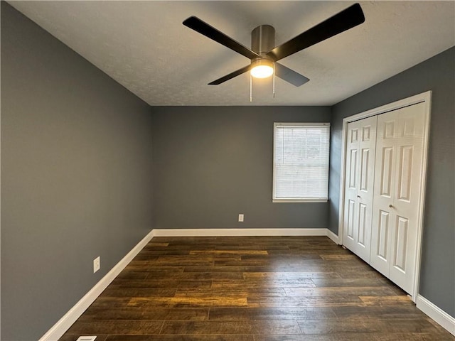 unfurnished bedroom featuring ceiling fan, dark hardwood / wood-style floors, and a closet