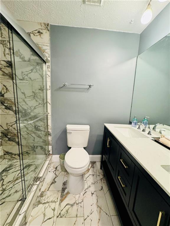 bathroom featuring vanity, an enclosed shower, a textured ceiling, and toilet