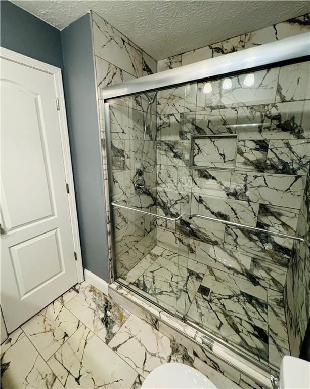 bathroom with toilet, a textured ceiling, and walk in shower