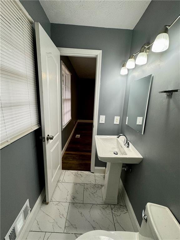 bathroom featuring sink, a textured ceiling, and toilet