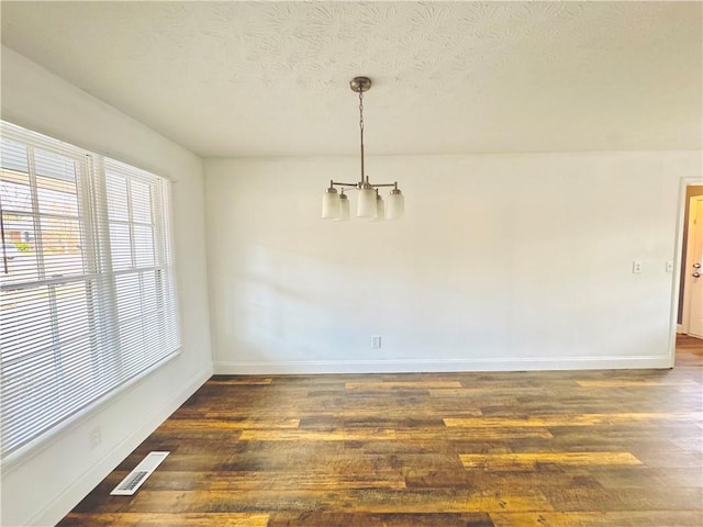 unfurnished dining area featuring a textured ceiling and dark hardwood / wood-style flooring