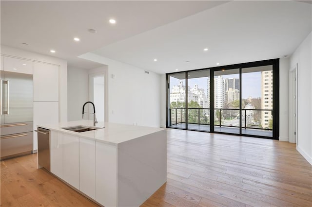 kitchen with expansive windows, appliances with stainless steel finishes, light wood-style floors, modern cabinets, and a sink