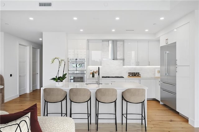 2425 Peachtree Rd NE Unit 903, Atlanta, GA 30305 - kitchen with modern cabinets, wall chimney exhaust hood, white cabinets, appliances with stainless steel finishes, and recessed lighting