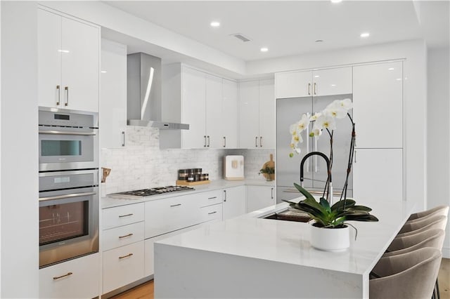 2425 Peachtree Rd NE Unit 903, Atlanta, GA 30305 - kitchen with modern cabinets, wall chimney range hood, double oven, white cabinetry, and a center island with sink