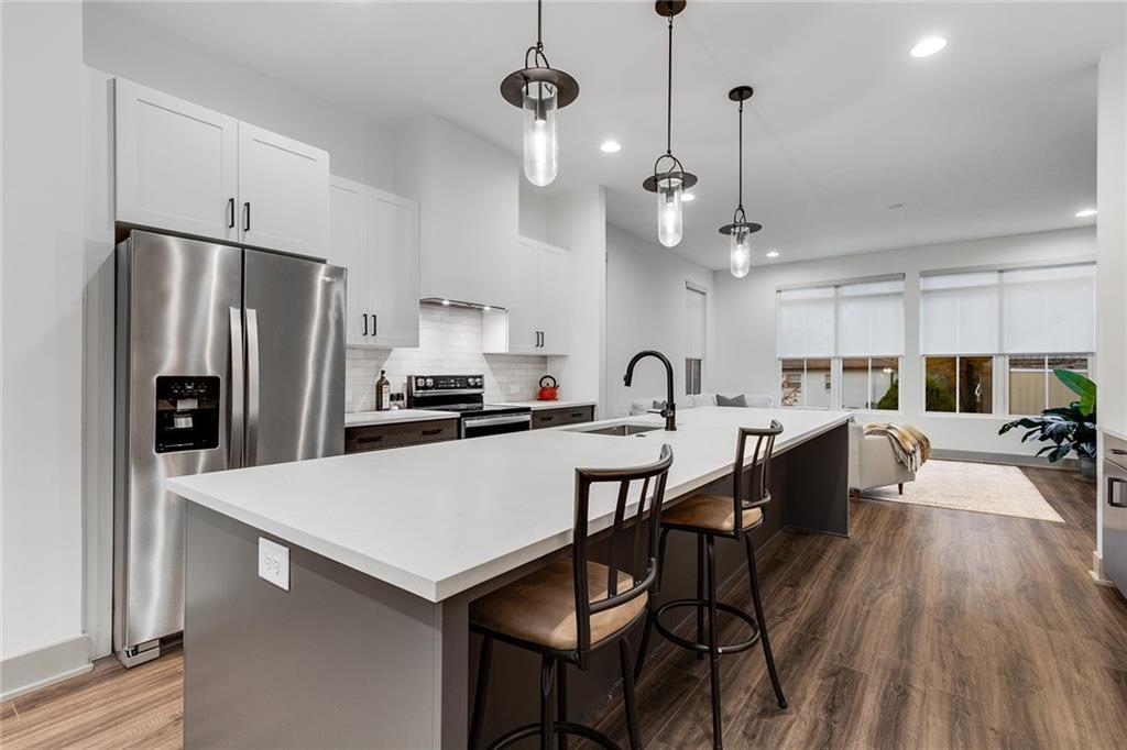 kitchen with a breakfast bar area, a center island with sink, white cabinets, and appliances with stainless steel finishes