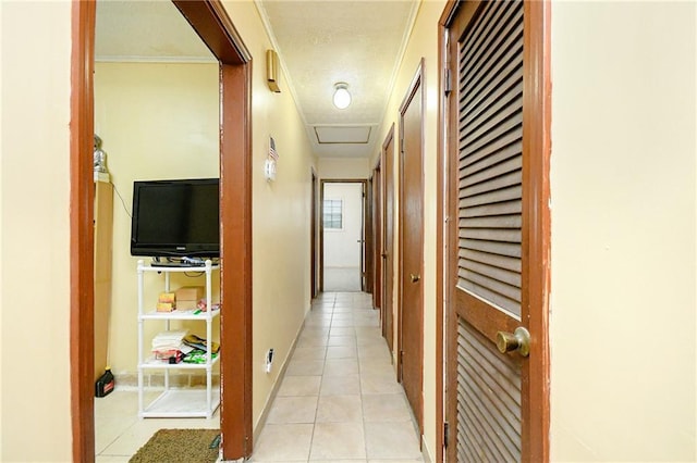 hallway with light tile patterned floors and attic access