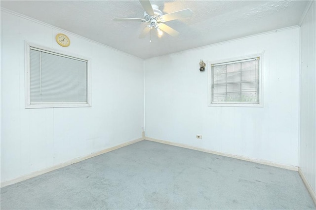 empty room featuring carpet flooring, ornamental molding, a textured ceiling, ceiling fan, and baseboards