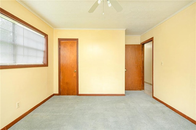 unfurnished bedroom with carpet flooring, baseboards, ornamental molding, and ceiling fan