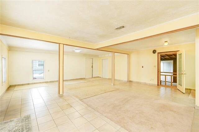 below grade area featuring light tile patterned floors, a textured ceiling, crown molding, baseboards, and light carpet