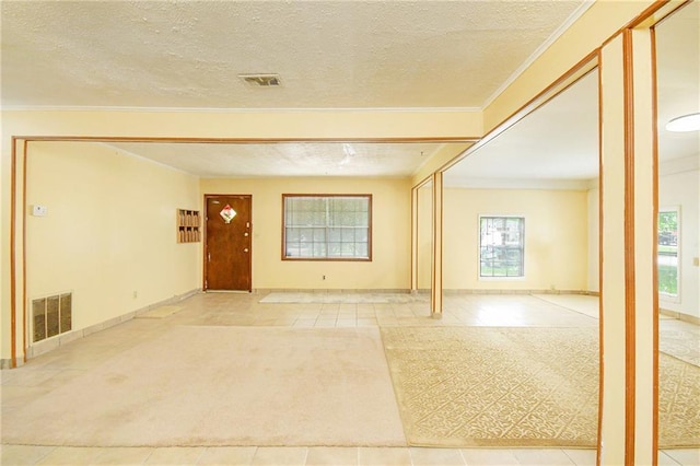 foyer entrance featuring tile patterned flooring, crown molding, carpet floors, a textured ceiling, and baseboards