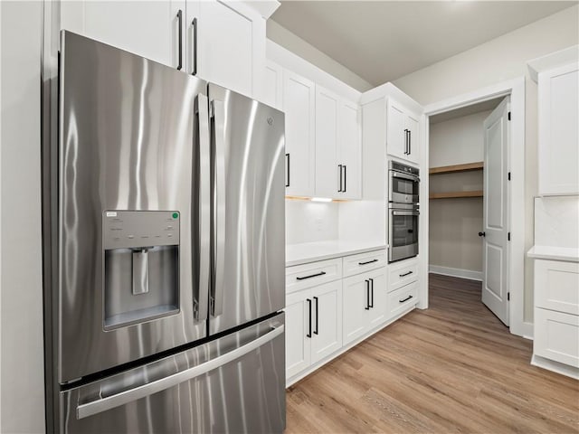 2335 Azalea Dr, Loganville, GA 30052 - kitchen with stainless steel appliances, light wood-style flooring, light countertops, and white cabinets