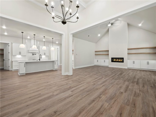 2335 Azalea Dr, Loganville, GA 30052 - unfurnished living room featuring light wood-style flooring, a chandelier, a high ceiling, ornamental molding, and a glass covered fireplace