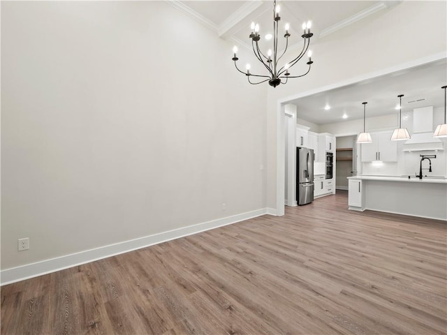 2335 Azalea Dr, Loganville, GA 30052 - unfurnished living room featuring light wood-style flooring, ornamental molding, and a chandelier