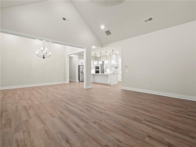 2335 Azalea Dr, Loganville, GA 30052 - unfurnished living room featuring a chandelier, high vaulted ceiling, and light wood-type flooring