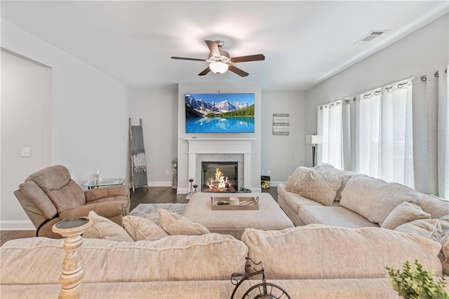 living area with baseboards, visible vents, a glass covered fireplace, ceiling fan, and wood finished floors