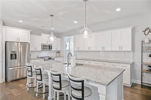 kitchen with stainless steel appliances, white cabinets, a sink, and dark wood-style floors