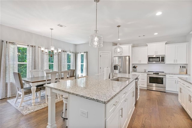 kitchen with visible vents, decorative backsplash, dark wood-style flooring, stainless steel appliances, and a sink