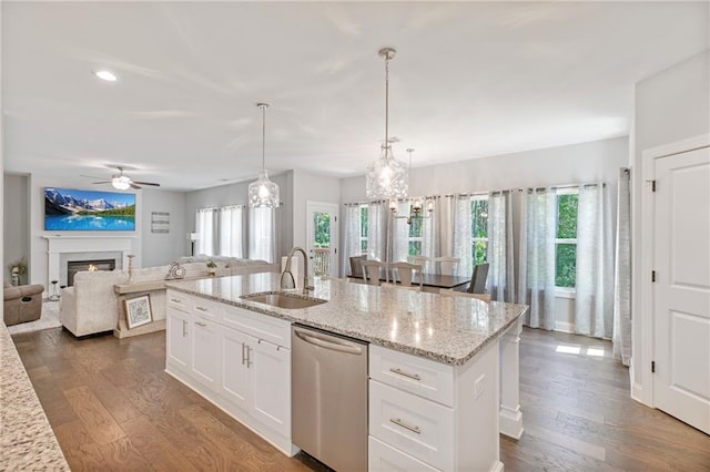 kitchen with a sink, a lit fireplace, dark wood-type flooring, and dishwasher