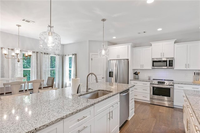 kitchen featuring white cabinets, decorative backsplash, appliances with stainless steel finishes, dark wood-style flooring, and a sink