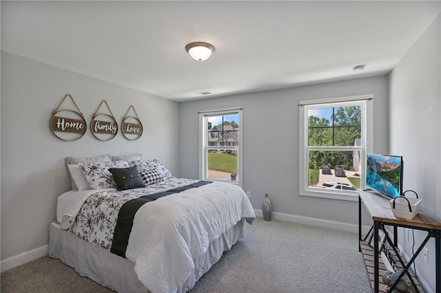 carpeted bedroom featuring multiple windows and baseboards