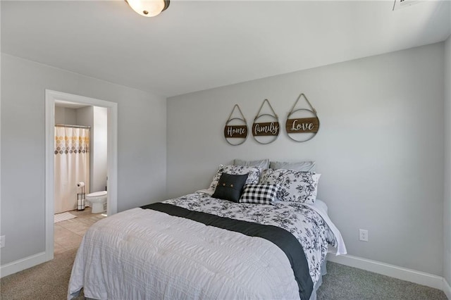 bedroom with light colored carpet, baseboards, and ensuite bathroom