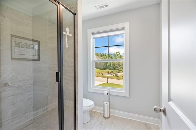 full bath featuring toilet, a shower stall, visible vents, and baseboards