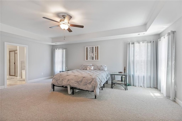 bedroom with a raised ceiling, light colored carpet, ceiling fan, and baseboards