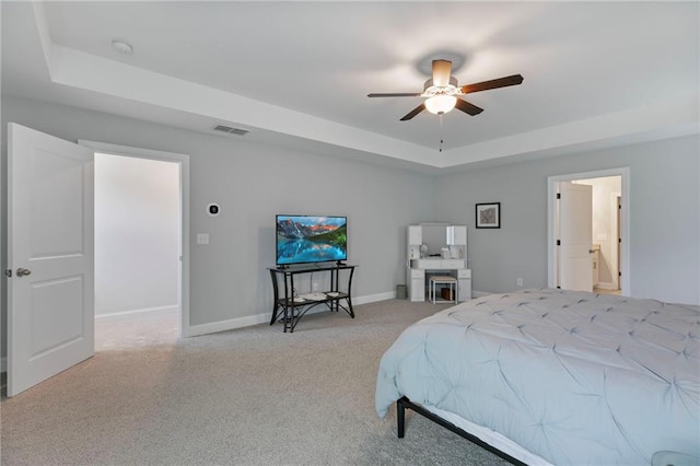 bedroom featuring a tray ceiling, light colored carpet, visible vents, and baseboards