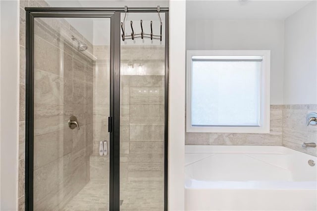 bathroom with a shower stall and a bath